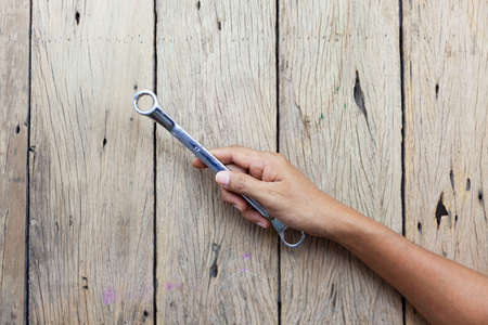 Carpenter hand holding wrench number 17 on old wooden table background.の写真素材