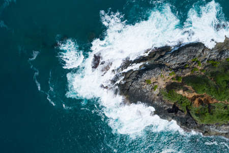 Aerial view Top down seashore big wave crashing on rock cliff Beautiful dark sea surface in sunny day summer background Amazing seascape top view seacoast at Phuket Thailand.の写真素材