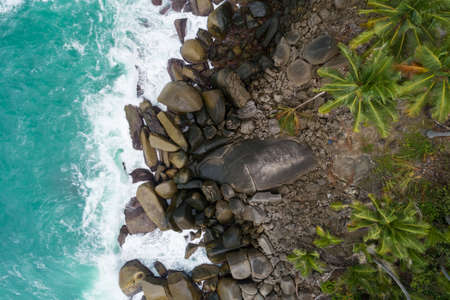 Aerial top view of sea waves crashing on rocks with coconut palm trees Beautiful seashore in Phuket Thailand Amazing nature seascape.の写真素材