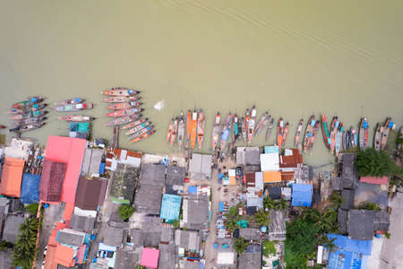 Aerial view top view of the fisherman village with fishing boats and house roof at the pier in suratthani Thailand. high angle viewの写真素材
