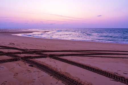 4x4 tyre tracks on sandy beach in andaman coast at sunset or sunrise sky over sea,Phuket island...