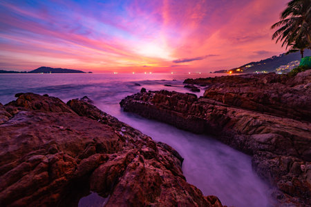 Long exposure image of Dramatic sky seascape with rocks and waves crashing on seashore in sunset or sunrise scenery backgroundの写真素材