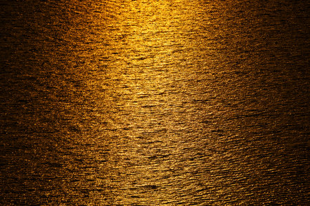 Full frame background of waves sea water rippling and reflecting golden sundown light,Sea surface...