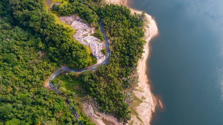 Top down from Drone aerial view of rainforest with asphalt road around the damの写真素材