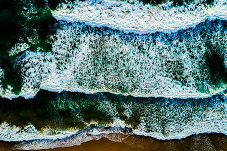 Top view Dark waves crashing on sandy shore beach background,Amazing waves sea nature backgroundの写真素材