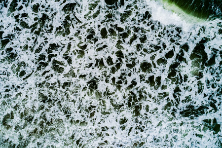 Top view Dark waves crashing on sandy shore beach background, waves sea nature backgroundの写真素材