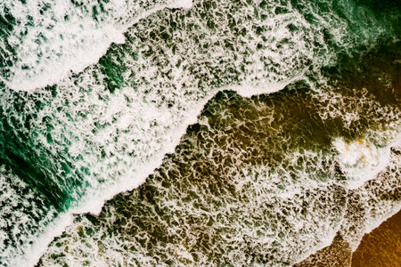 Aerial view Top down Waves crashing on sandy shore,Dark sea surface in summer day...