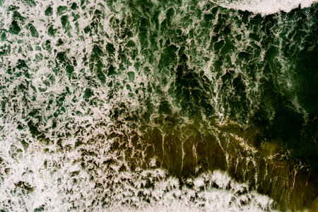 Aerial view Top down Waves crashing on sandy shore,Dark sea surface in summer day...
