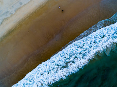Aerial view Top down Waves crashing on sandy shore,Dark sea surface in summer day...