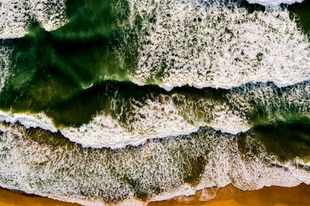 Aerial view Top down Waves crashing on sandy shore,Dark sea surface in summer day...