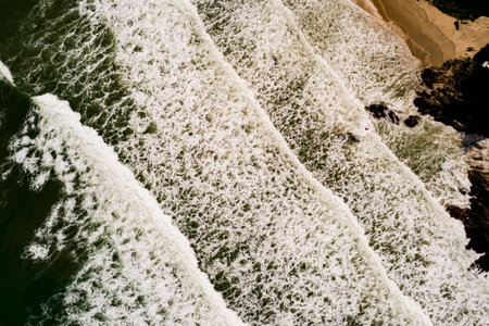 Aerial view Top down Waves crashing on sandy shore,Dark sea surface in summer day...