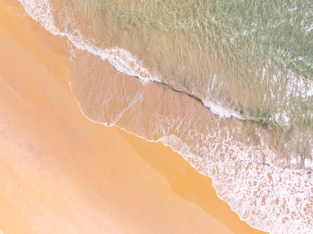 Top view beach with waves crashing on sandy shore,Beautiful waves sea surface in summer seascape background,Amazing beach colorful water backgroundの写真素材