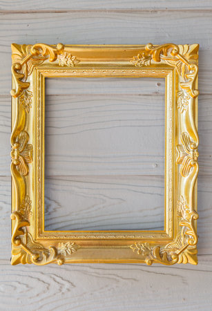 Empty golden frame on a wooden backgroundの写真素材