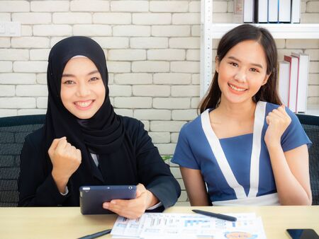 Two Muslim businesswomen are discussing company earnings happily in the modern office.の写真素材