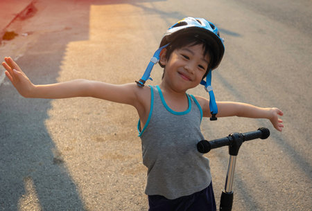 A 4-year-old Asian boy smiled happily with the opportunity to exercise by riding a scooter in the eveningの写真素材