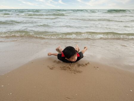 A 4-year-old Asian boy doing planking exercise on beachの写真素材