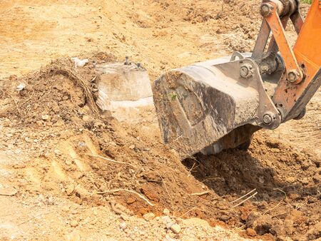 The machinery is digging the ground to lay the foundation for lighting the electric pole on the construction road.の写真素材