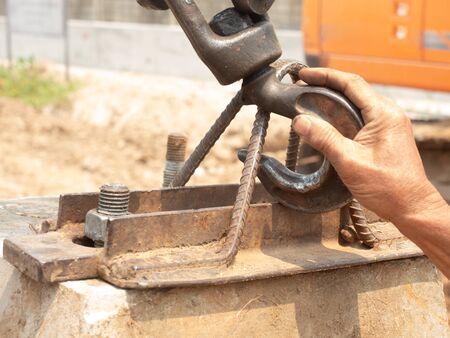The right hand of the worker is holding the hook to fasten on the bracket for lifting the material to move with the crane.の写真素材
