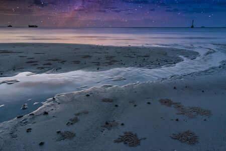 The beach during low tide at night, in the sky there are many beautiful starsの写真素材