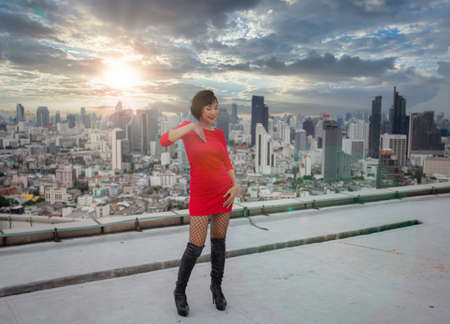 A female hip hop dancer in a snakeskin costume is dancing happily at the top of a high-rise building.の写真素材