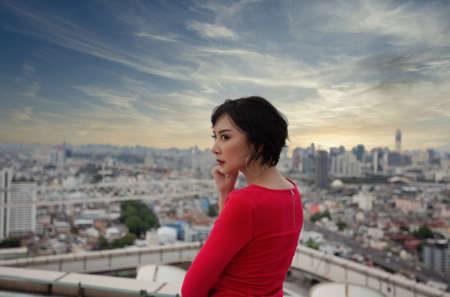 A female hip hop dancer in a snakeskin costume is dancing happily at the top of a high-rise building.の写真素材