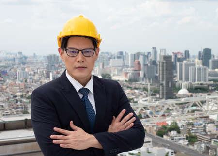 Portrait of real estate businessman. Front view businessman standing cross one's arm for planing in the concept of real estate and engineering at top of buildingの写真素材