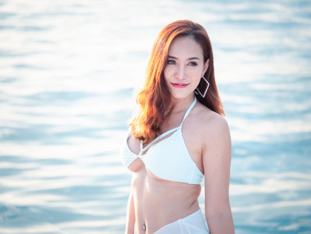 Portrait of a smiling attractive Asian woman bikini sexy resting and relaxing at a luxury yacht travel lifestyle, a happy female enjoying life playing, and freedom at sunset.の写真素材