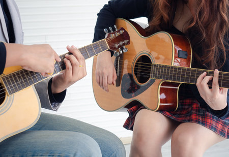 Woman practice while sitting on a chair. The teacher's hand-touching strings explain cords, the basics of playing the guitar, the lifestyle conceptの写真素材