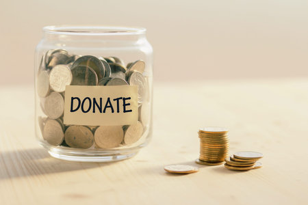 Coins in glass jar with DONATE word written text label for giving and donation concept