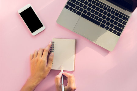 Man write on notebook  Modern pink office desk with laptop and other supplies with cup of coffee
for input the text on copy space Top view, flat lay.の写真素材