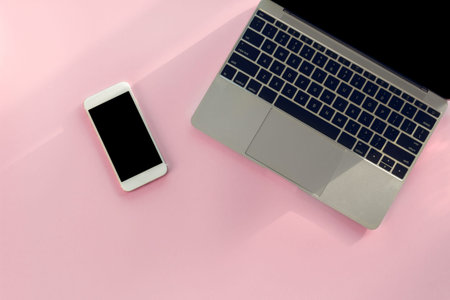 Modern pink office desk with  laptop smartphone and other supplies with cup of coffeefor input the...