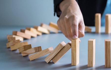 businessman hand stop dominoes continuous toppled or risk with copyspace