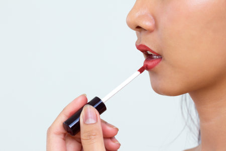 Close up cropped shot  Women Tan Health. applying  light beige liquid lipstickの写真素材