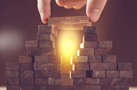 success in business planning, risk and strategy in business, businessman gambling placing wooden block on a towerの写真素材