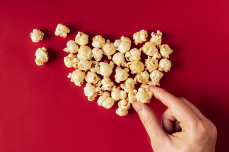 popcorn blast heart shape hand pick  with corn on red isolated
