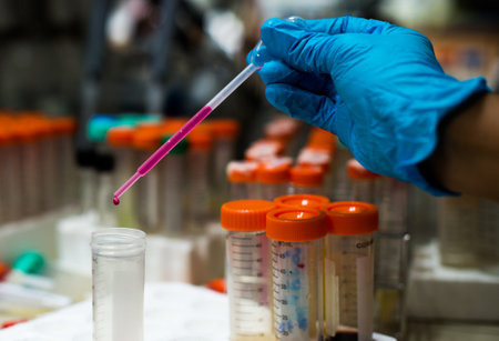 Pipette dropping a sample into a test tube, closeup