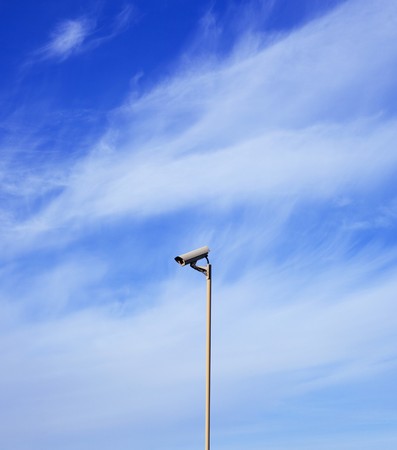 Singl video surveillance camera over the background of blue skyの写真素材