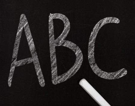 learning the alphabet in a primary school, drawing with chalk on a blackboard