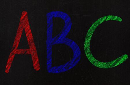 learning the alphabet in a primary school, drawing with chalk on a blackboardの写真素材