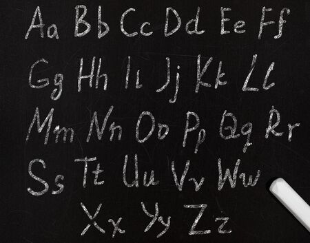 learning the alphabet in a primary school, drawing with chalk on a blackboardの写真素材