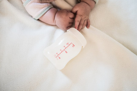 Baby hand and Bottle of Mother breast milk on white blanket background for text spaceの写真素材