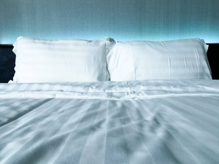 close up white pillow on comfort white bed. background concept for relaxation and bedroomの写真素材