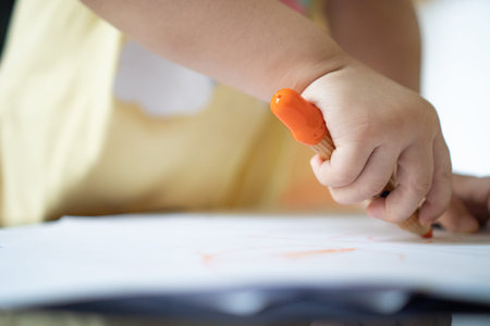 Close up hand of 2 years kid use color pencil draw line on paper. Concept of art for children...