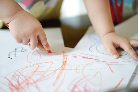 Close up hand of 2 years kid use color pencil draw line on paper. Concept of art for children learning. Education and  imaginationの写真素材