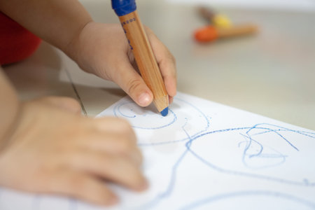 Close up hand of 2 years kid use color pencil draw line on paper. Concept of art for children...