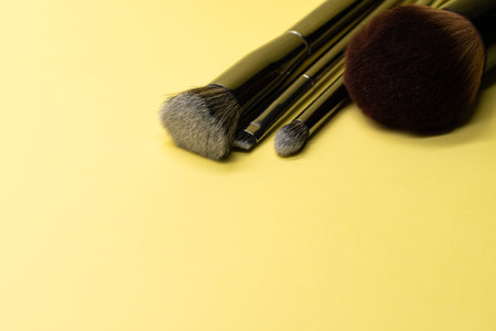 Professional makeup brushes with silver handle on yellow background with copy space. Concept for...