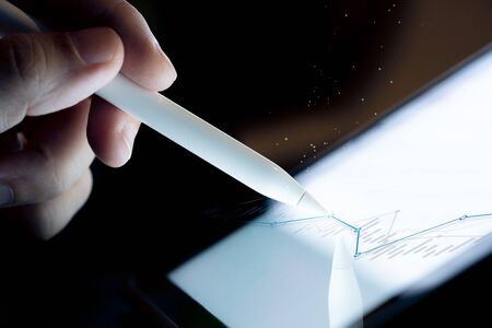 Hand use  pen stylus touch business graph  on Tablet screen Mock up with light. Concept for mobile phone technology and business look.の写真素材