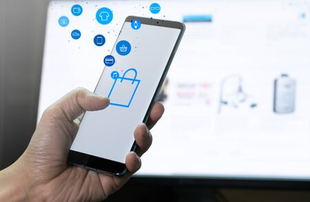 mobile phone in hand with shopping button and product icon flow. Concept for mobile application technology and online e-commerce.の写真素材