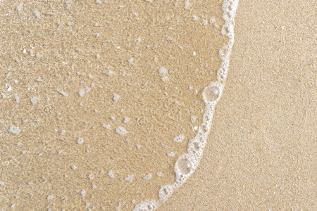 Close up ocean wave bubble on sandy beach. Background for vacation holiday and natural feeling.