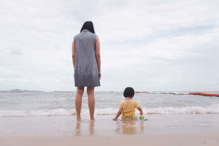 Mother and 3 years old asian kid playing on the beach. Background for family vacation and recreation.の写真素材